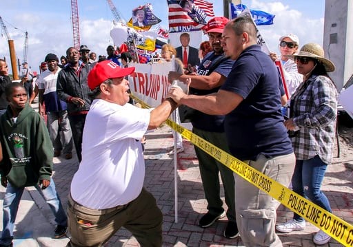 (Damon Higgins/Palm Beach Post via AP). A President Donald Trump supporter, left, confronts a fellow Trump supporter, right, who was speaking on a bullhorn, to stop being disrespectful and spewing hate Monday, Jan. 15, 2018, as local Haitians march in ...