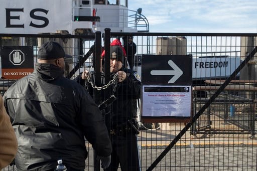(AP Photo/Mary Altaffer). A United States Park Police officer, center, locks a gate leading to a Statue of Liberty ferry, Saturday, Jan. 20, 2018, in New York. The National Park Service announced that the Statue of Liberty and Ellis Island would be clo...