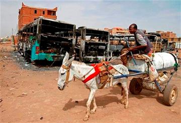 (AP Photo/Abd Raouf, File). FILE - In this Thursday, Sept. 26, 2013 file photo, a man on a donkey cart passes burned buses following rioting and unrest in Khartoum.